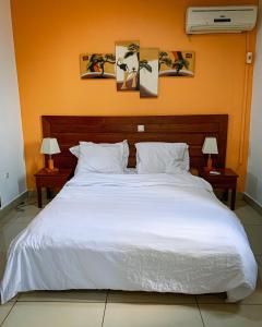 sypialnia z dużym białym łóżkiem z 2 lampami w obiekcie Appartement élégant proche de Yaoundé Centre w mieście Jaunde