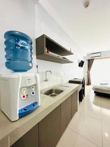 a kitchen with a sink and a water cooler on the counter at Super Deluxe Apartment with Skypool Medan in Sunggal