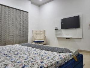 a bedroom with a bed and a chair and a flat screen tv at Amritsar Homes - A perfect home away from home in Amritsar