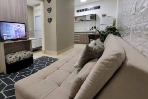 a living room with a white couch and a television at Flat Morada da Neblina! in Chapada dos Guimarães