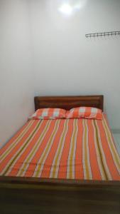 1 cama con edredón de rayas naranja y amarillo en JM resort en Trincomalee