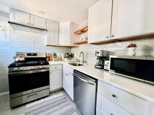 a kitchen with white cabinets and a black stove at Ultra Modern - Entire 3 Bedroom Apartment - 5 min walk to the Beach in Wildwood +11 photos