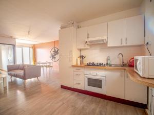 een keuken met witte kasten en een woonkamer bij T2 Équipé - bas de la possession in La Possession