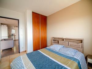 een slaapkamer met een bed met een blauw en wit dekbed bij T2 Équipé - bas de la possession in La Possession