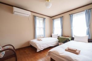 two beds in a room with two windows at Lodge Kent in Hokuto