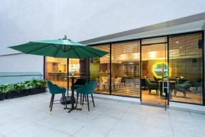 a patio with a table with a green umbrella at SCAPES Hotel in Genting Highlands