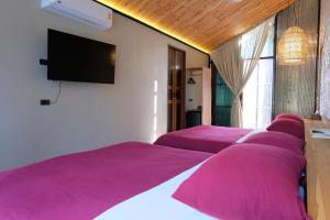 a row of purple beds in a room with a flat screen tv at STAY PILAFarm in Ban Nam Chun Yai