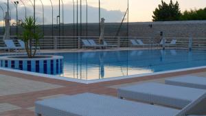 a swimming pool with white chairs and a potted plant at Hotel Boutique Il Castellino Relais in Vieste