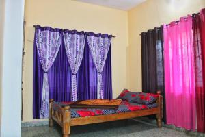 Cette chambre dispose de rideaux violets et d'un banc en bois. dans l'établissement Pearl Stay, à Madikeri