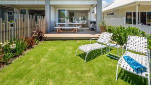 a patio with two chairs and a table on a lawn at Watersea By The Bay Unit 2, waterfront, walk to shop&restaurants in Umina