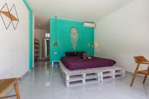 een slaapkamer met een paars bed en een blauwe muur bij Balifornia Villa Canggu in Canggu