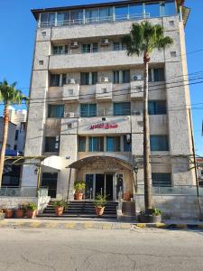 un bâtiment avec un palmier en face dans l'établissement Aghadeer Hotel, à Amman