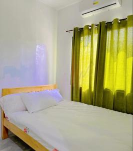 a bedroom with a bed and a yellow curtain at My Lovely Apartment in Dipolog