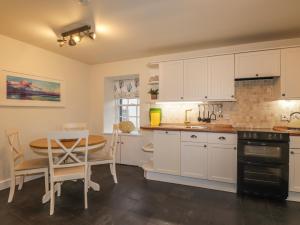 een keuken met witte kasten en een tafel en een eetkamer bij Lydia Cottage - Cromarty in Cromarty