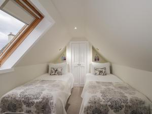 two beds in a attic room with a window at Lydia Cottage - Cromarty in Cromarty