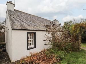 een klein wit huis met een raam bij Lydia Cottage - Cromarty in Cromarty