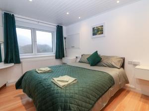 a bedroom with a bed with green sheets and windows at Llety'r Wyddfa in Caernarfon