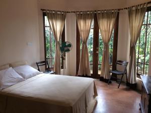 a bedroom with a bed and large windows at Mount Haven in Kandy