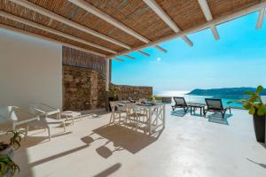un patio esterno con sedie, tavoli e vista sull'oceano di Elia House With Amazing View On The Beach Mykonos a Mykonos Città