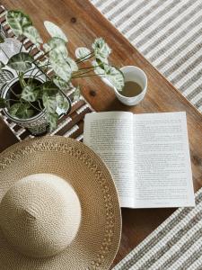 een tafel met een boek en een hoed en een bord bij "On Burgum Pond" Cottages in Maleny