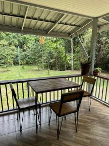 a wooden table and two chairs on a porch at บ้านสวนริมธาร โฮมสเตย์ ท้ายเหมือง พังงา in Ban Nai