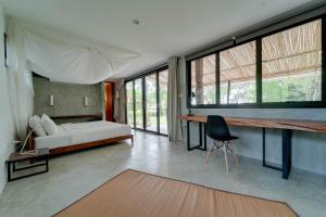 een slaapkamer met een bed, een bureau en een aantal ramen bij Costa Lanta - Adult Only in Koh Lanta
