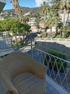 un fauteuil en osier sur un balcon avec vue sur la ville dans l'établissement appartamento incantevole a Ospedaletti(Sanremo), à Ospedaletti