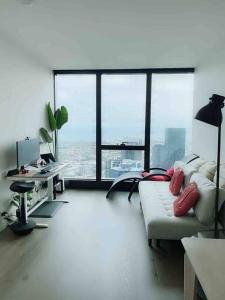 a living room with a couch and a desk and windows at Sky Home - Ocean view 2 BR with Sunrise and Sunset views in Melbourne