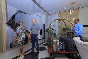 a man and a woman standing in a room with a cart of luggage at Zemilo Hotel Apartment in Addis Ababa