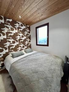 ein Schlafzimmer mit einem Bett in einem Zimmer mit einer Kuhwand in der Unterkunft Nid de charme au pied des pistes in Saint-Martin-de-Belleville