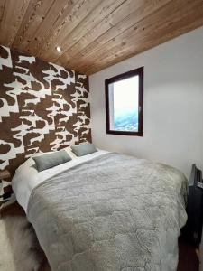 a bedroom with a bed in a room with a cow wall at Nid de charme au pied des pistes in Saint-Martin-de-Belleville