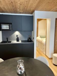 eine Küche mit einem Tisch und eine Küche mit einem Bett in der Unterkunft Nid de charme au pied des pistes in Saint-Martin-de-Belleville