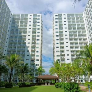 two tall buildings with a gazebo in front of a park at Chillax Condotel - Shore Residences in Manila