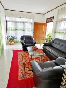 a living room with two leather couches and a red rug at Mountain Paradise Homestay in Bandarawela