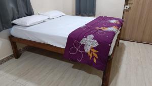 a bed with a purple blanket on top of it at The Royal Ascot Holiday Home in Alibaug