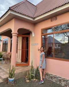 a woman standing in front of a house at ZIMBE HOST Apartment in Arusha