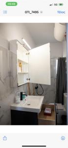 y baño con lavabo blanco y espejo. en Neapolis apt lycabetus view en Athens