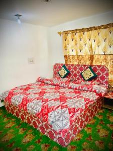 a bedroom with a bed with a red and white quilt at Al Hayat Guest House in Pahalgām