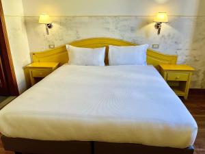 フィレンツェにあるホテル ドゥーカ ダオスタのテーブル2台付きの客室で、白い大型ベッド1台が備わります。