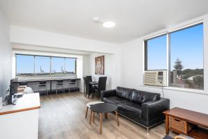 a living room with a black leather couch and a desk at Apartment 201 - Fremantle studio apartment with ocean and harbour views in Fremantle