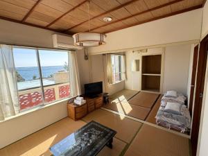 - un salon avec vue sur l'océan dans l'établissement ビーチサイドペンションみーばる, à Nanjō