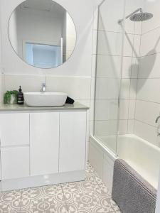 La salle de bains blanche est pourvue d'un lavabo et d'un miroir. dans l'établissement 83 Appin - Newly renovated house, à Wangaratta