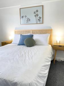 Elle comprend un grand lit avec des draps blancs et des oreillers bleus. dans l'établissement 83 Appin - Newly renovated house, à Wangaratta