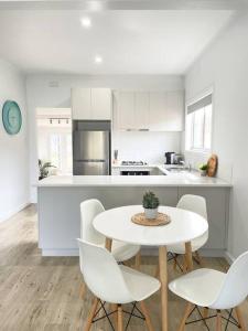 - une cuisine blanche avec une table et des chaises dans l'établissement 83 Appin - Newly renovated house, à Wangaratta