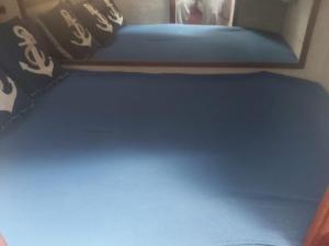 Cama en habitación con sábanas y almohadas azules en Barco acogedor en el puerto del másnou, en Masnou