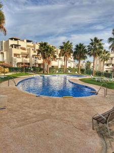 uma piscina com palmeiras em frente a um edifício em VeraTespera - Apartamento en Vera Playa - Mascotas em Vera