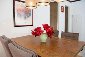 a vase with red flowers sitting on a wooden table at Cristallina holiday flat for 4 people Lenzerheide in Lenzerheide