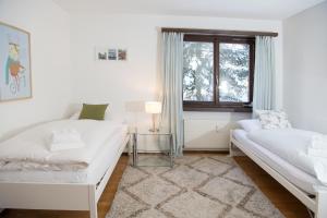 a white room with two beds and a window at Cristallina holiday flat for 4 people Lenzerheide in Lenzerheide