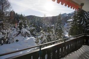 a balcony with snow covered trees and a building at Cristallina holiday flat for 4 people Lenzerheide in Lenzerheide