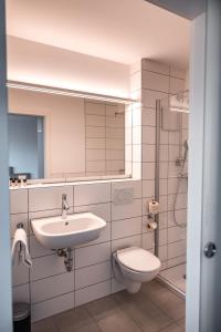 ein Badezimmer mit einem Waschbecken, einem WC und einem Spiegel in der Unterkunft Hotel am Schlossberg in Herrenberg
